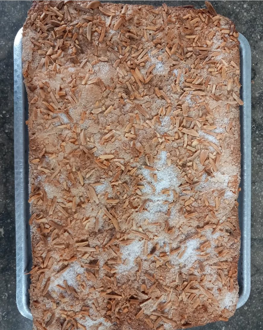 Coca rectangular coberta d'ametlla laminada i sucre, sobre una safata de metall