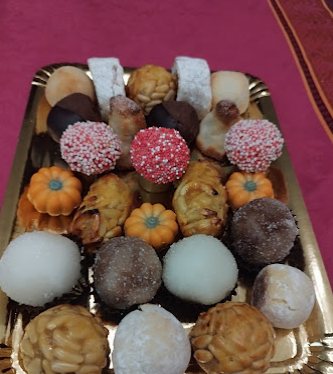 Safata daurada plena de panellets de diferents sabors i formes, amb pinyons, coco i xocolata