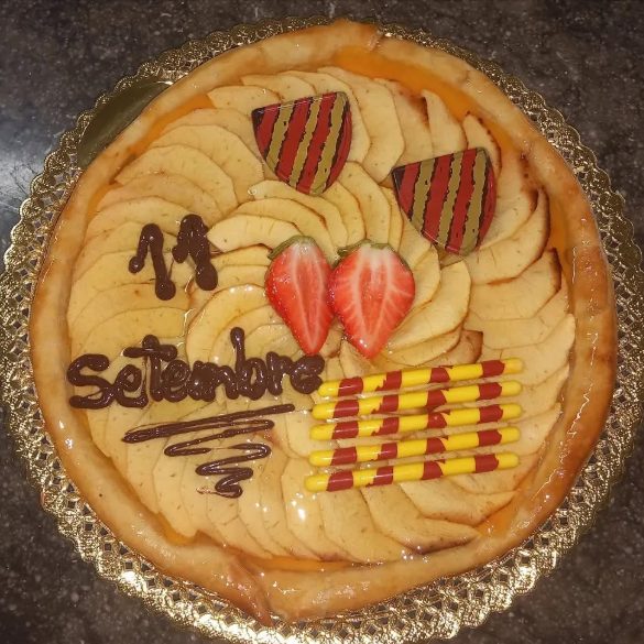 Pastís de pomes en rodanxes decorat amb dos escuts de xocolata, la senyera i la inscripció «11 Setembre»