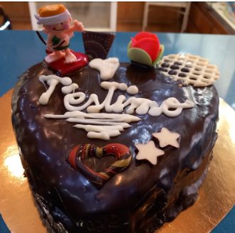 Pastís de xocolata en forma de cor amb la inscripció «T'estimo», estrelles de xocolata blanca i una figureta