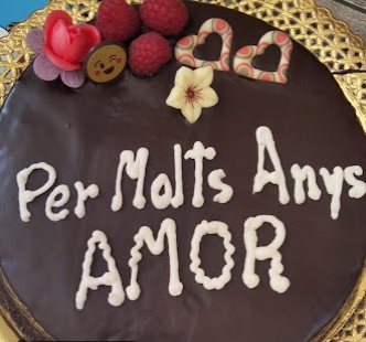 Pastís Sacher cobert de xocolata, amb una dedicatòria en xocolata blanca i fruits vermells a sobre